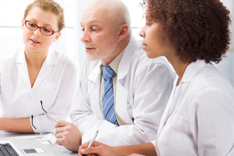 Three healthcare workers looking at a computer screen. Two women, One man